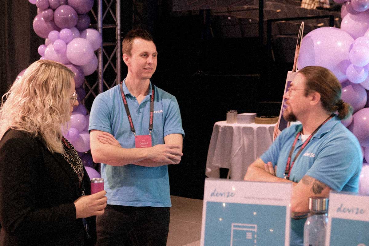 Devize medarbetare pratar med en besökare i montern på Sitevision-dagarna